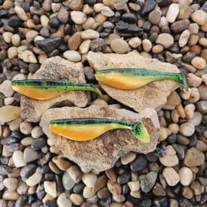Three colorful, handmade clay pins on small rocks and pebbles.