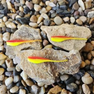 Colorful feathers placed on rough rocks among pebbles.