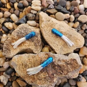 Three blue glitter fishing lures on rocks.