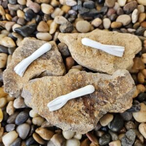 Three white fishing lures on rocks.